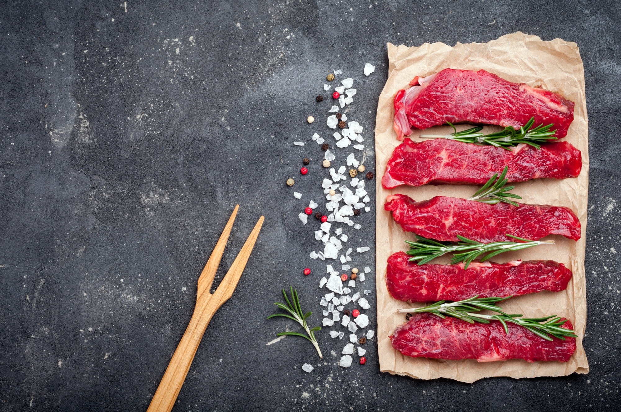 Raw meat on dark background. Raw beef stroganoff with herbs and spices. Cooking meat
